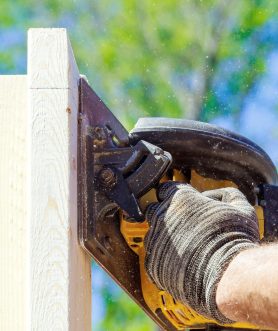 Process of cutting wooden beams using handsaw by woodworking carpenter